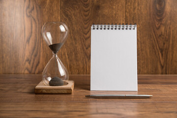 Hourglass and notebook on the table