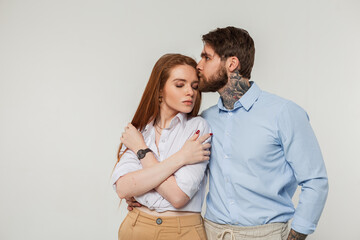 Fashion couple beautiful redhead woman and handsome hipster man in elegant fashionable clothes stands and poses on a white background