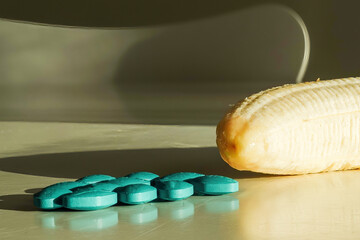 Impotence pills and a peeled fresh banana on a table