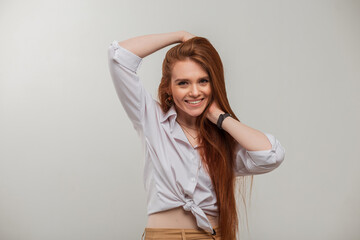 Fototapeta premium Happy redhead fashion fresh girl with a cute smile in a white shirt poses on a white background in the studio