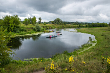 A landscape with floating kayaks along a pure river untouched by civilization with herbs along the banks.