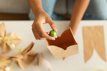 Easter Gift Ideas. Female Hands Putting Chocolate Egg Into Craft Paper Bag