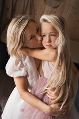 mother and daughter blonde with long hair hug and kiss each other. Mother's love, tenderness and care. The daughter is offended and sad, offended. Woman comforting a child at home. High quality photo