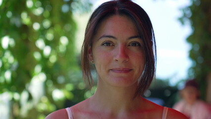 Portrait of a woman in 30s looking at camera standing outside. Close up of female person face