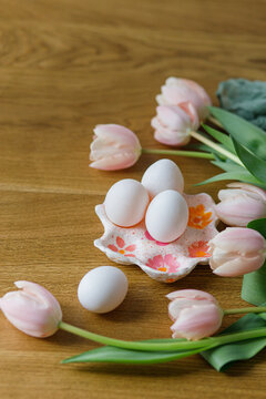 Happy Easter! Beautiful tulips and eggs on wooden table. Modern farmhouse easter decor. Stylish handmade egg holder with natural eggs and pink tulips
