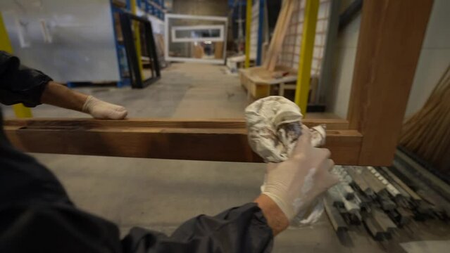 Handheld shot of male hands in white rubber gloves cleaning polishing a new wooden frame. Male hands holding a rag varnishing oiling. Slow motion