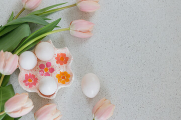 Beautiful tulips and natural eggs on modern table. Stylish easter flat lay with copy space. Happy Easter! Handmade egg holder with pink tulips