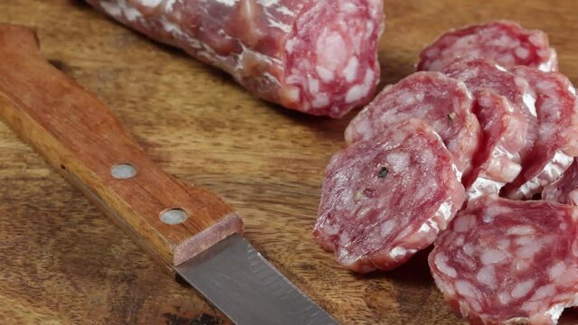 saucisson sec tranch&eacute; en gros plan sur une table en bois	