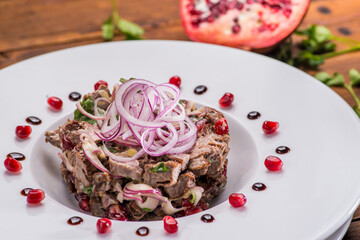 Meat salad with onions in a white plate