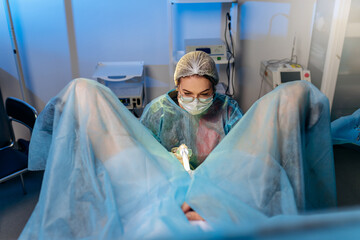 Professional female surgeon proctologist performing operation using special devices for colonoscopy...