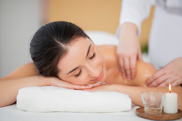 Fototapeta na wymiar Smiling indian woman enjoying relaxing body massage in spa salon