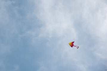 Fototapeta na wymiar Colorful kite toy flying in the sky among clouds