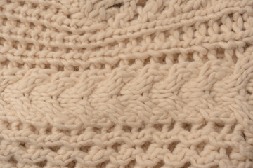 A fragment of beige knitted fabric, knitted from white sheep wool.