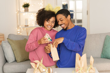 Happy black couple preparing easter presents together at home