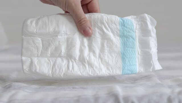 baby stack many diapers on bed woman mother hand taking one or pressing push with palm.white empty diaper throwing on bed slow motion maternity child infant new born toddler care concept