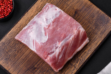 Fresh juicy pork on a wooden cutting board with spices and salt
