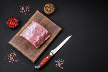 Fresh juicy pork on a wooden cutting board with spices and salt