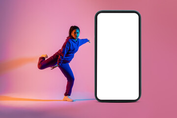 Professional dancer jumping near huge smartphone with white blank screen, pink neon background,...
