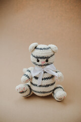 knitted white and black striped teddy bear with a large white, satin butterfly on the neck