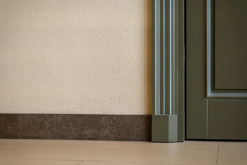 View of a closed door inside an office or cafe. Beige tiles on the floor and granite baseboards...
