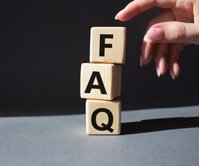 FAQ - Frequently Asked Questions symbol. Concept word FAQ on wooden cubes. Businessman hand....