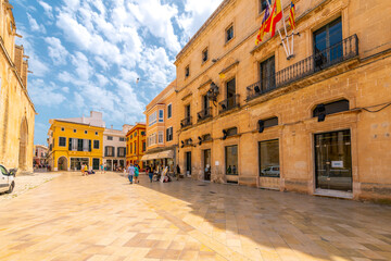 A colorful street of shops and cafes at the Ciutdadella Cathedral Plaza square in the medieval old town district of Ciutadella de Menorca, Spain. - obrazy, fototapety, plakaty