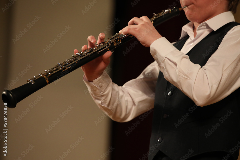 Wall mural Person playing the black clarinet details of a musical instrument in the hands of a young musician close up