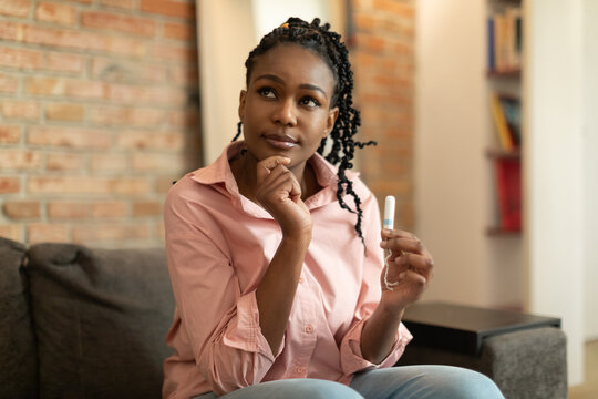 Hesitant Black Woman Thinking What Better To Choose During Critical Days, Holding Menstrual Tampon And Thinking