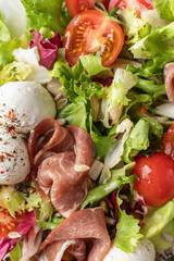 Fresh salad with Prosciutto, salad mix, cherry tomatoes, mozzarella cheese close up top view. Healthy food, keto diet, diet lunch concept