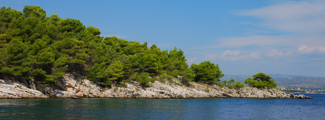Fototapeta na wymiar Rocky limestone coast of the Adriatic Sea covered with pine forest. Croatia coastline.