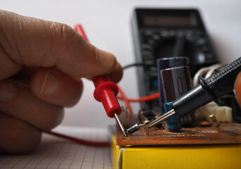 Close up of a hand holding multimeter probes. Focused on diode. Technical service department .