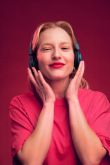 Portrait of a happy blond woman listening to music while smiling at the camera.