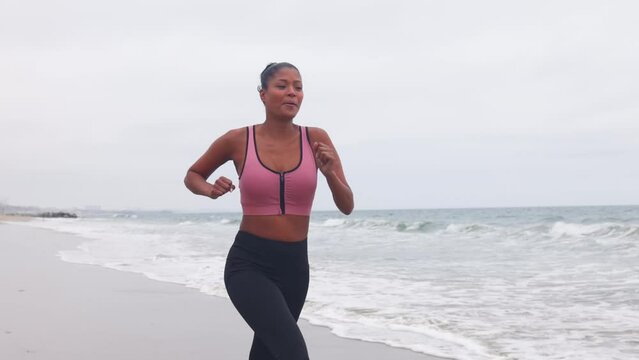Mixed ethnicity (Asian-African) woman jogging at the beach