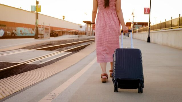 Asian woman walking through a train station with her suitcase.