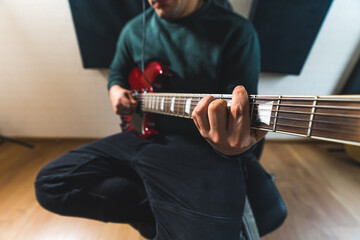 young man working on bass guitar and creating a new melody. High quality photo