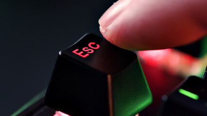 Man finger hovers over the Esc key for a few seconds before deciding to press it. Yes or no concept. Person is in doubt whether to press the escape key or not. Heavy decision do it or not.