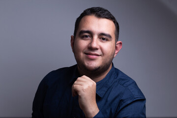 hombre profesional con camisa azul sonriente frente a un fondo blanco 