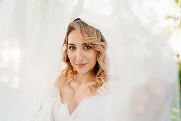 portrait under the veil. a beautiful blonde bride in a white dress.