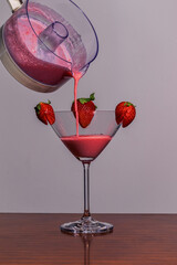 Batido de fresa en una copa de vidrio adornado con tres fresas.