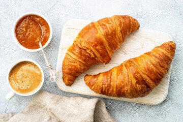 Croissant with jam and cup of coffee at white stone table. Traditional snack or breakfast. Flat lay.