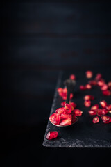pomegranate seeds on an old vintage spoon isolated on stone table. copy space for text. vintage style