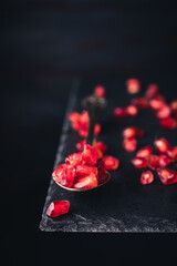 pomegranate seeds on an old vintage spoon isolated on stone table. copy space for text. vintage style