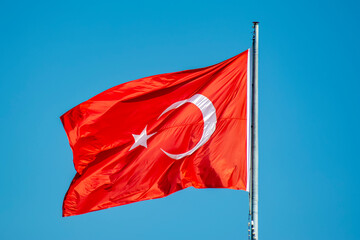 Turkish national flag waves in the breeze against the blue sky background