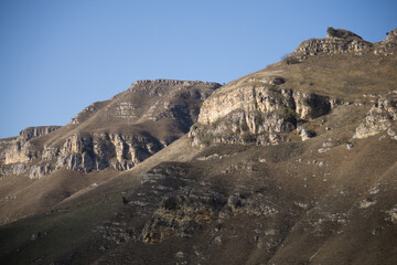 Mountain range with rocky cliffs and ridges made of stones in the mountains at sunset in the evening, the texture of the mountain range