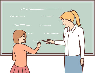 Female teacher and schoolgirl writing on blackboard