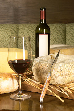 Assortment of different types of cheese on wooden table with red wine, cheese still life, food