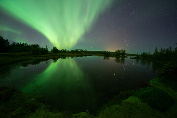 Bright aurora borealis mirror reflection in lake, Thingvellir Iceland