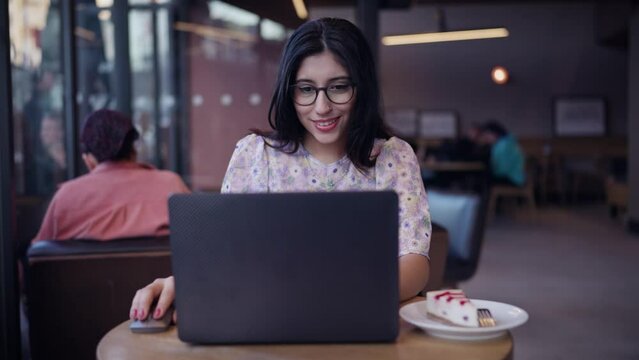 Nice multi race brunette beautiful young woman. Female portraits. Sitting at table in cafe. Female sitting in front open laptop computer. Study, learning, remote work, freelance.