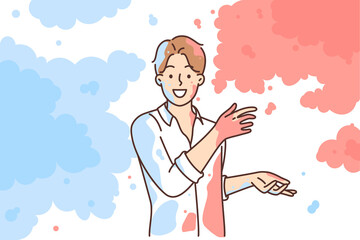 Man in white shirt scatters multi-colored powder on sides, wanting to share bright emotions