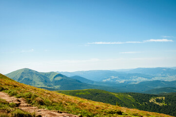 Fototapeta na wymiar summer landscape, green peaks of mountain hills against the background of the morning blue sky